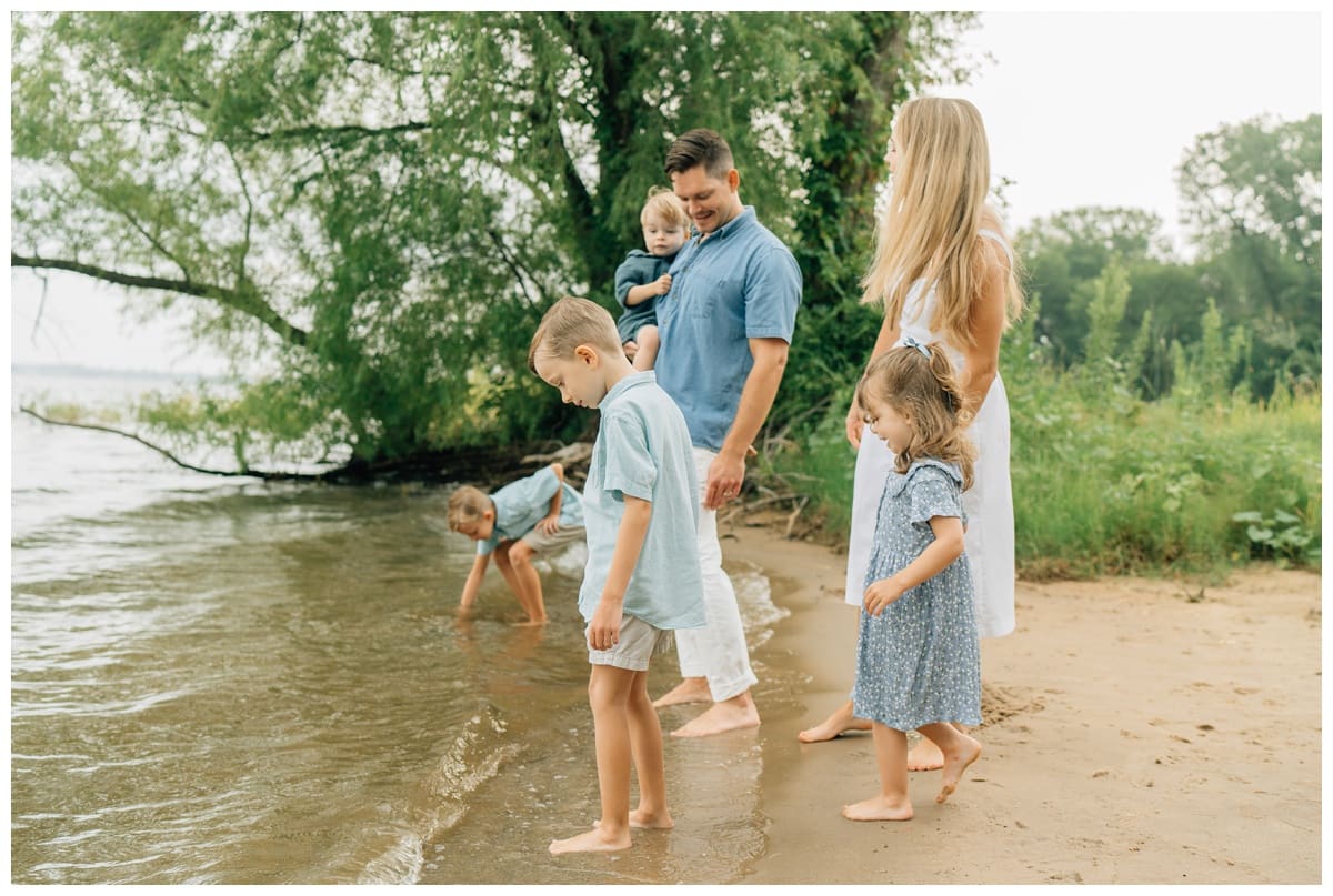 Family enjoying time together at the Oklahoma lake shore, walking in the water and cuddling by the trees, captured naturally to show what is lifestyle photography in action.