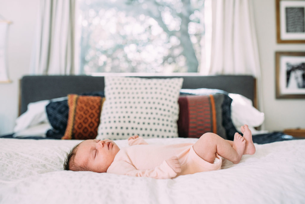 infant girl laying on bed during photography session with lifestyle newborn photographer Haley Kinzie