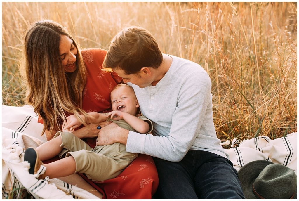 Dad and mom tickle toddler boy during family photos