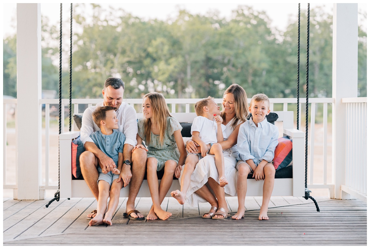 Family sitting on porch swing for family pictures at Carlton Landing