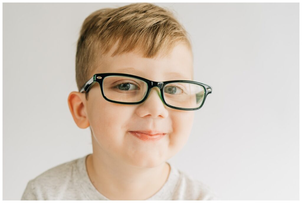 young boy sitting for preschool school portraits in school portrait photography setup
