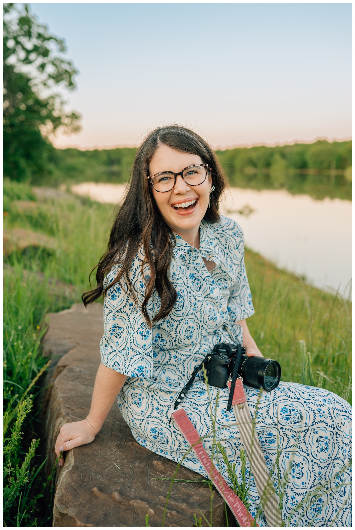 Photographer, Haley Kinzie, sitting on a rock outdoors with camera in hand for portrait.