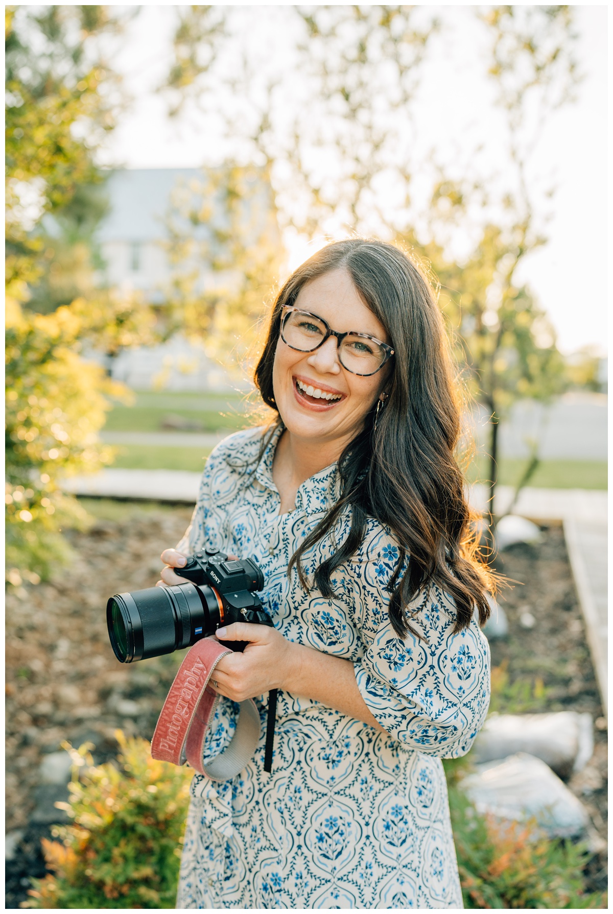 Photographer, Haley Kinzie, holding camera in outdoor portrait in Carlton Landing.