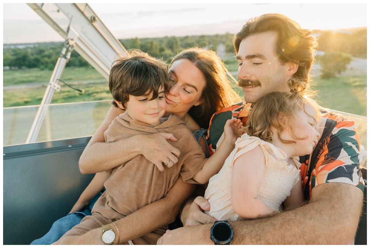 Sunset family pose cuddled together on a ride, with daughter asleep in father’s arms.