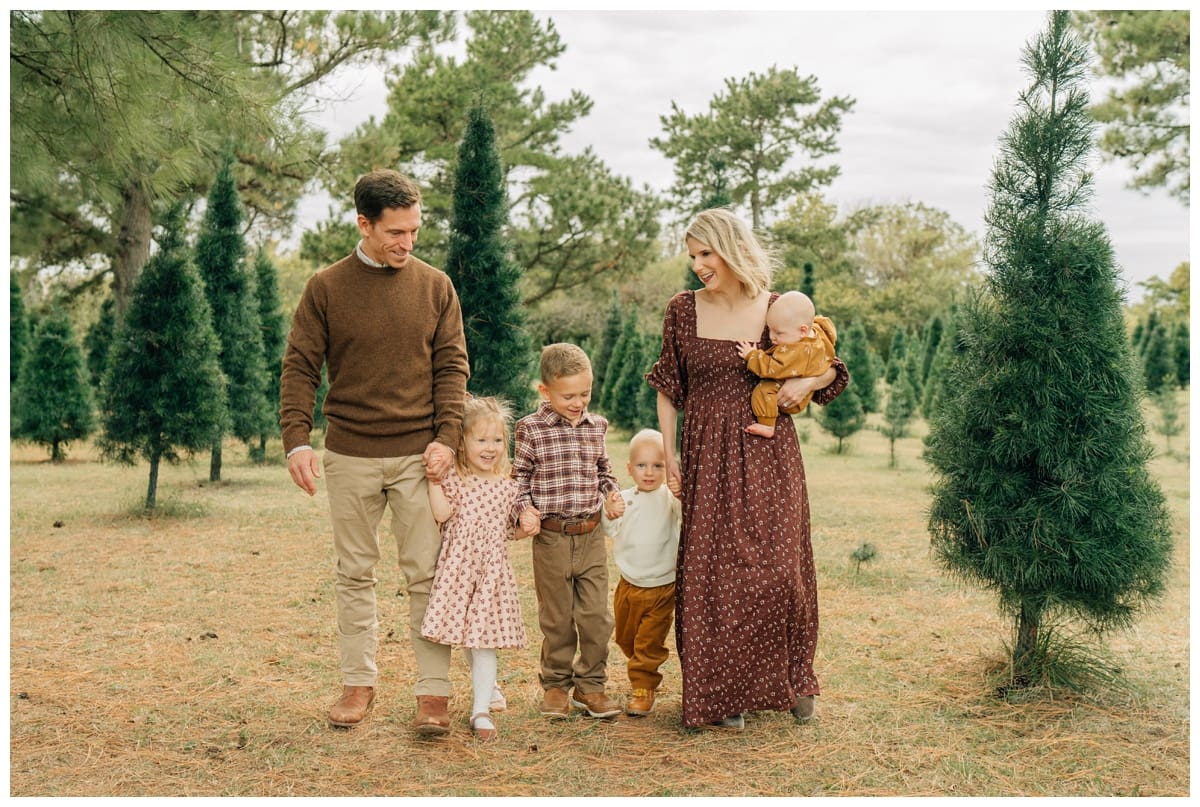 Family of five posing at Christmas farm for family photos.